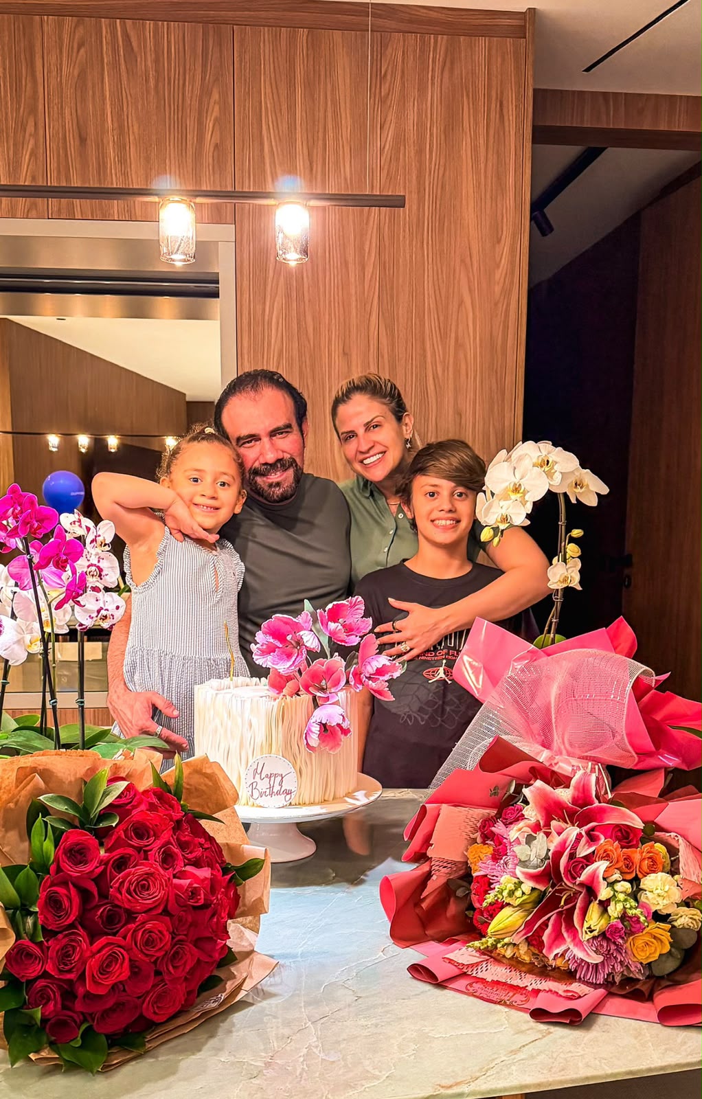 Geovana Costa ao lado do esposo, Dr. Ricardo Araújo, e dos filhos Marina e Eduardo, com bolo e flores de aniversário