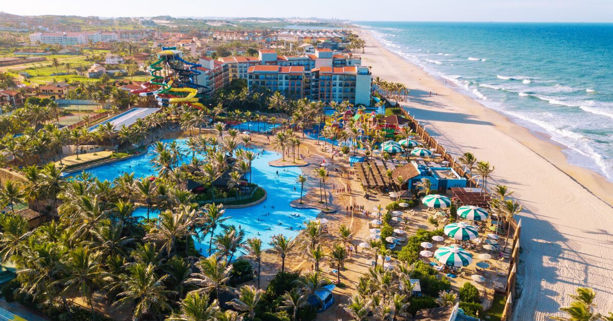 Vista aérea do Beach Park, em Fortaleza, com piscinas, toboáguas coloridos, coqueiros, guarda-sóis e a praia ao lado